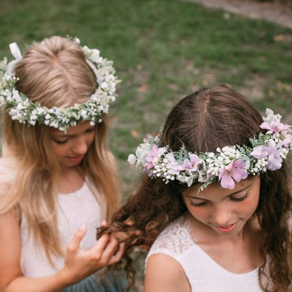 Two young girls wearing floral crowns outdoors.