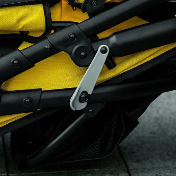 Folded pet stroller joint and metal latch, close-up on yellow-and-black frame