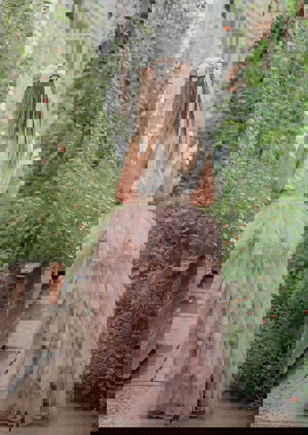 young girl in gardens wearing pretty dress in latte colours