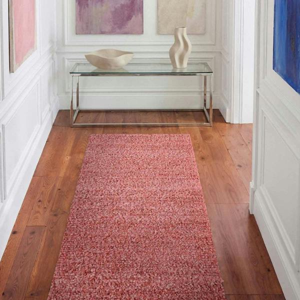 Red runner rug on a wooden floor with a glass table and abstract art in the background.