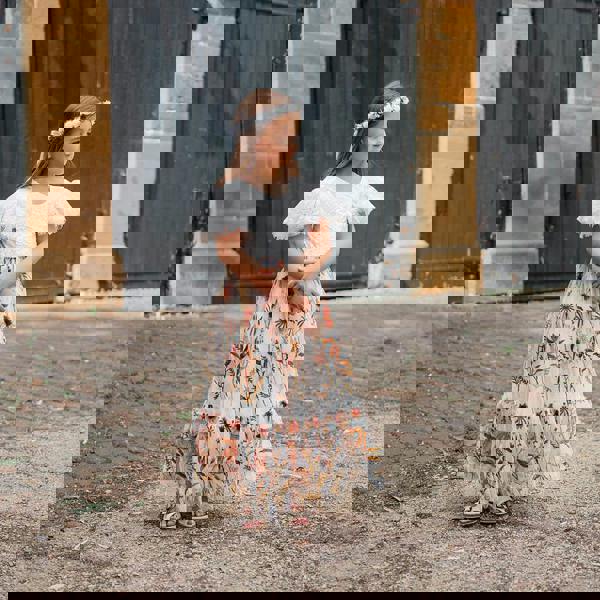 Young girl in a floral dress standing in front of large doors.