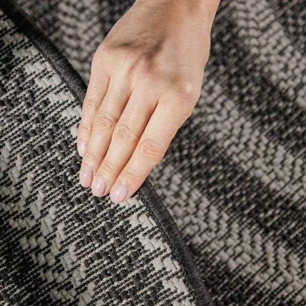 Hand touching a textured gray and black fabric surface