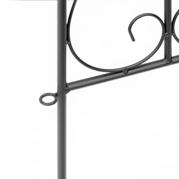 Close-up of black metal fence lower rail with curled scroll loop and round ring