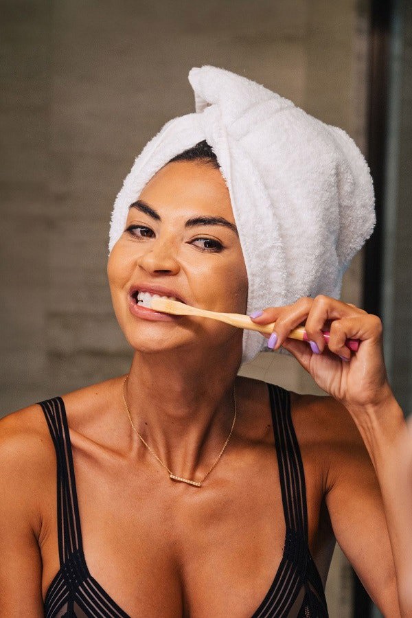 smiling lady brushing teeth with bamboo toothbrush