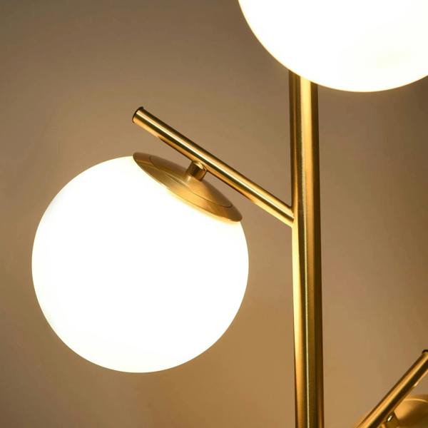 Gold three-light floor lamp with round white globe shades and gold metal arms
