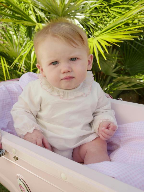 Baby in pink trim frill collar blouse with jersey body underneath and long sleeves.