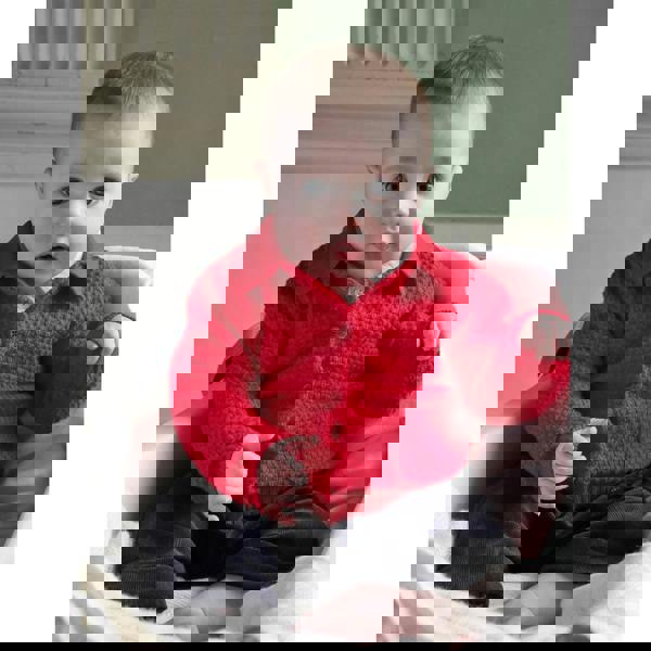 Baby boy wearing red moss stitch cardigan, styled with brown babycord trousers.