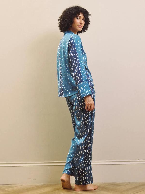 Woman wearing blue and white fawn patterned pyjamas against a beige wall.