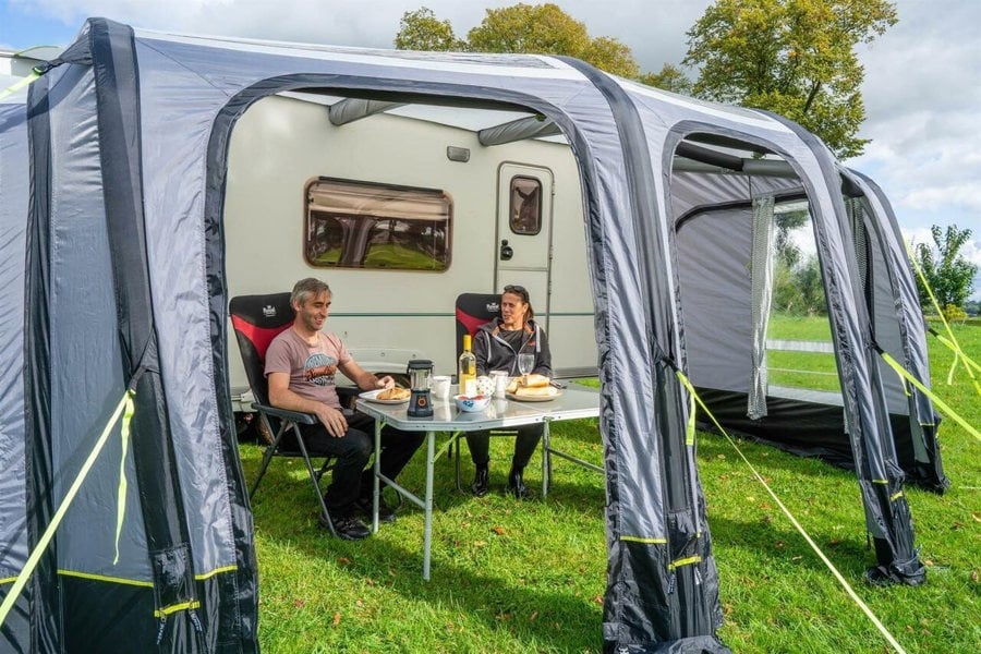 An image of a male and a female enjoying lunch inside the OLPRO View 420 Caravan Inflatable Porch Awning With Porch Extension.