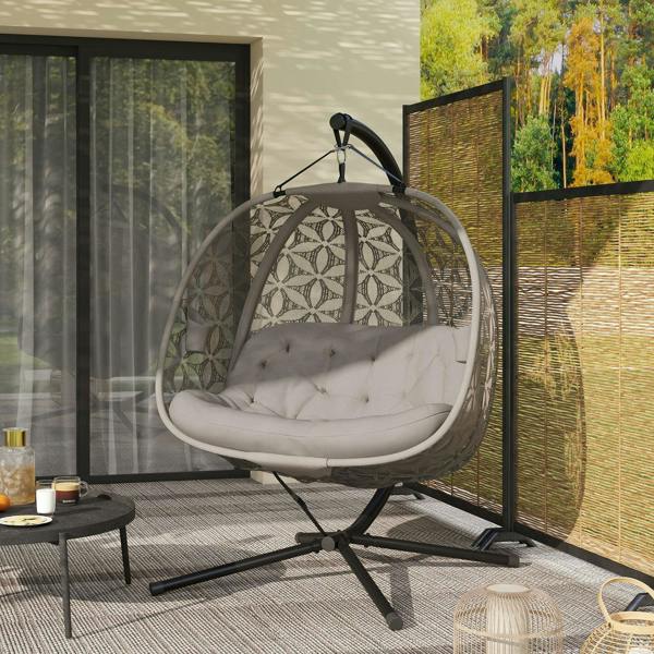 Outdoor hanging chair with patterned canopy and padded seat cushion on black stand