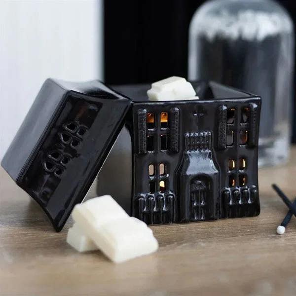 Black haunted house oil burner with open lid, wax cubes, and wick on display