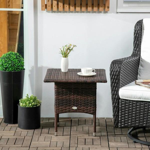 Brown woven rattan-style outdoor side table with square top beside potted plants