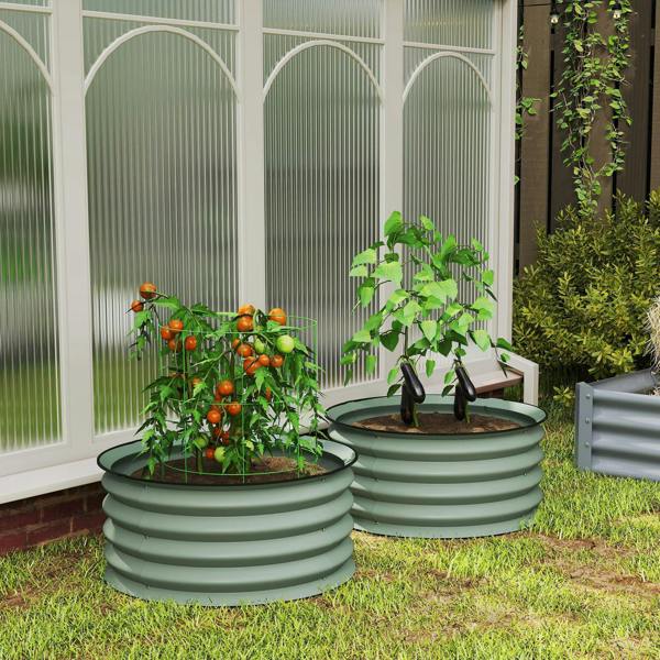 Two green ribbed metal stock tank planters with tomato plants