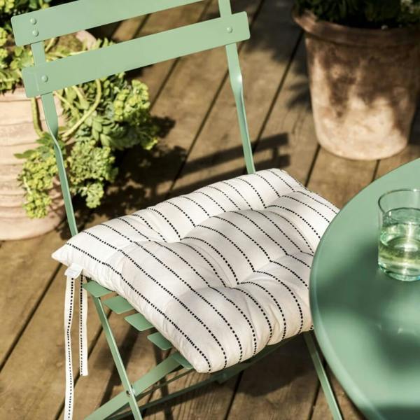 Grey and white striped tufted seat pad cushion tied to a green garden bistro chair