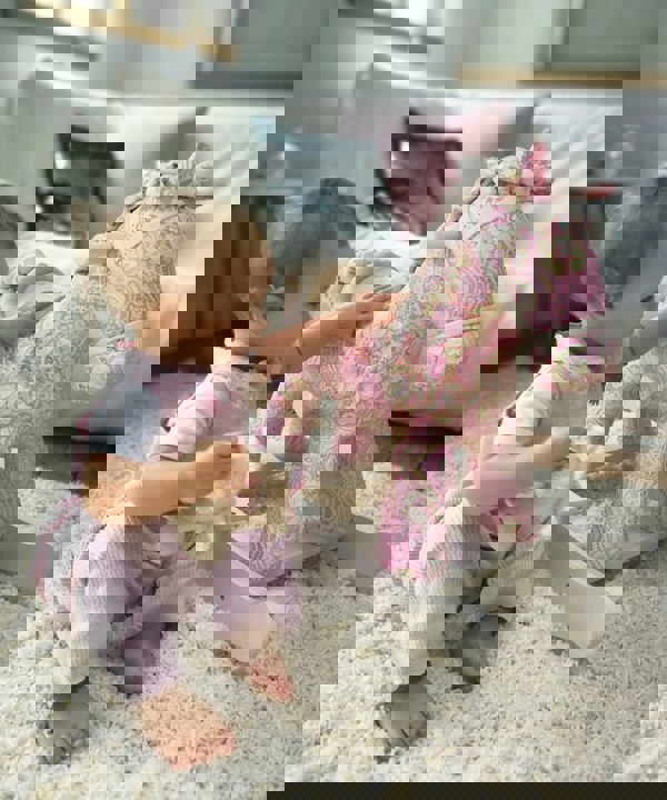 Baby girl playing with paisley pink Pixie & Fluff Rocking Horse on a cream rug