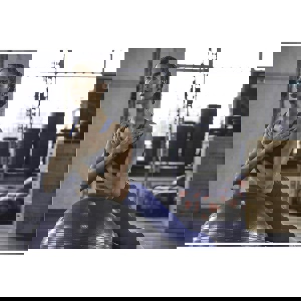 Woman working out in the gym using an Adidas 65cm Gym Ball 