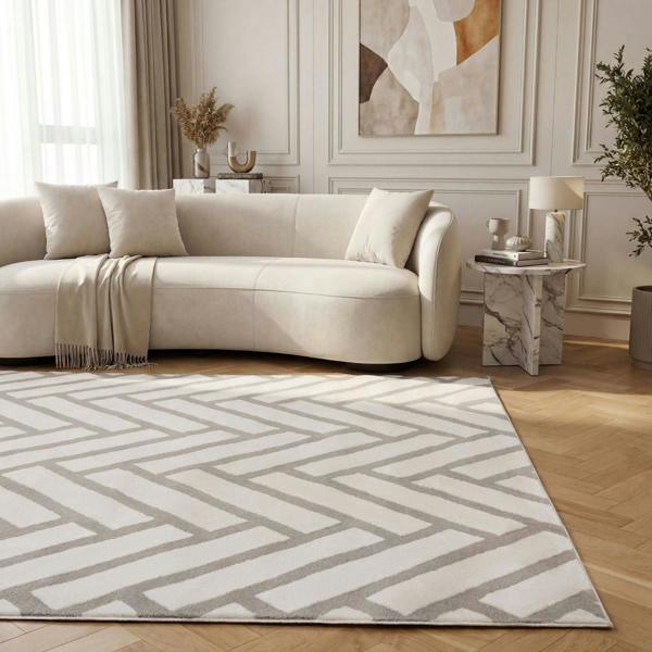 Living room with a beige sectional sofa, geometric patterned rug, and abstract art on the wall.
