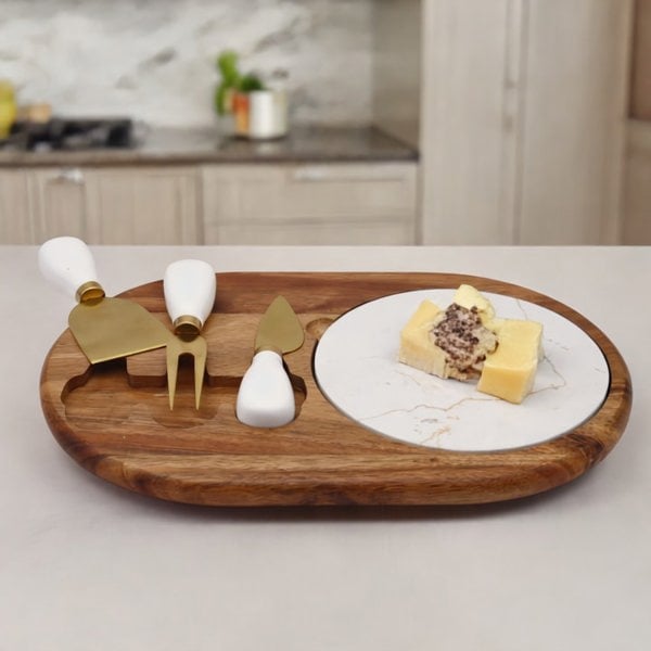 Wooden cheese board with marble insert, cheese, and cheese tools on a kitchen counter.