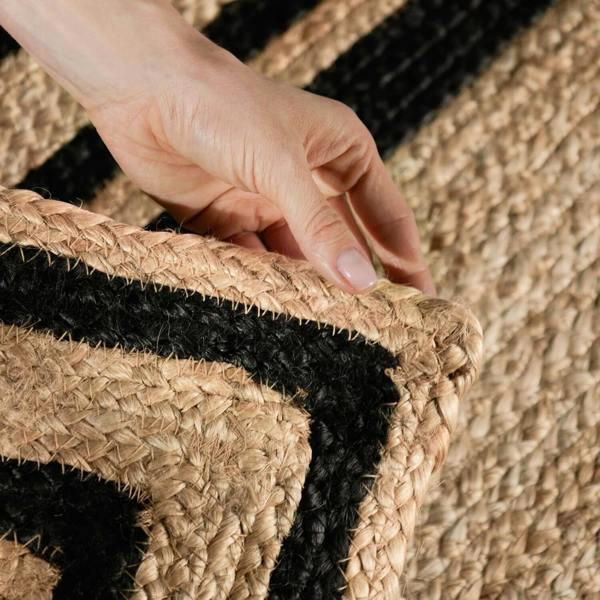 Hand touching a woven mat with black and beige pattern