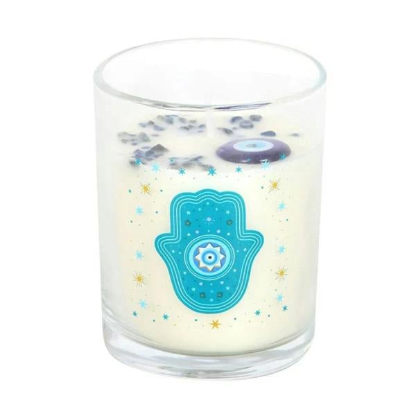 Clear glass candle with creamy wax and scattered blue stars; teal hamsa eye emblem