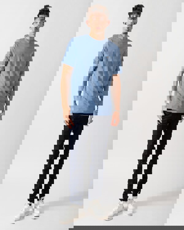 full length of a Model wearing a GANT Mens Regular Fit Short Sleeve Shield Logo T-Shirt in Faded Denim