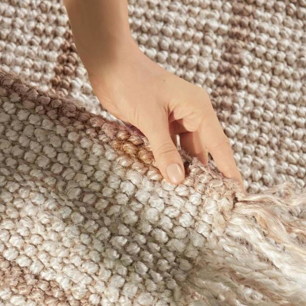 Hand touching a textured beige rug