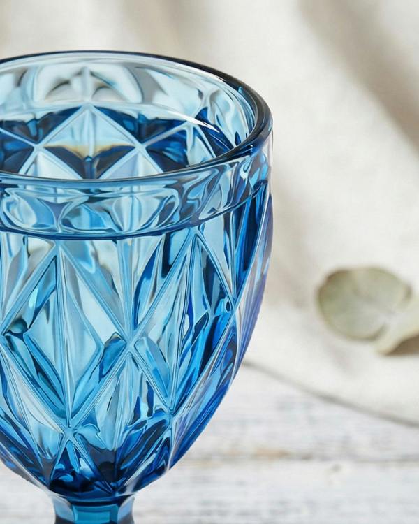 Blue glass with diamond pattern on a light wooden surface