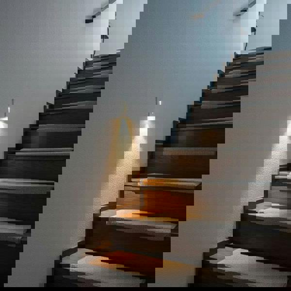 white motion sensor step light installed on a white wall next to a stairway