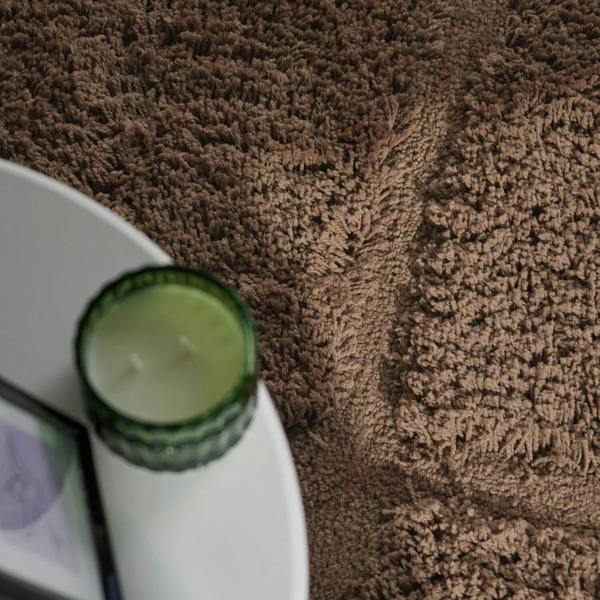 Green candle on a white plate with a brown textured surface