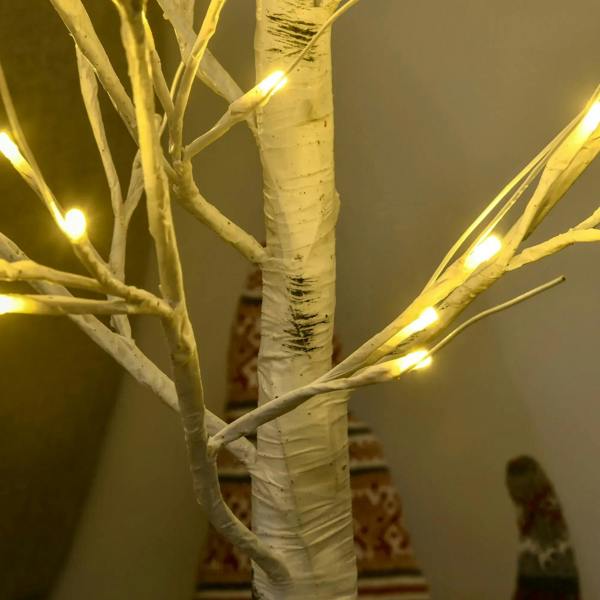 Close-up of white birch trunk and glowing warm white LED light branches