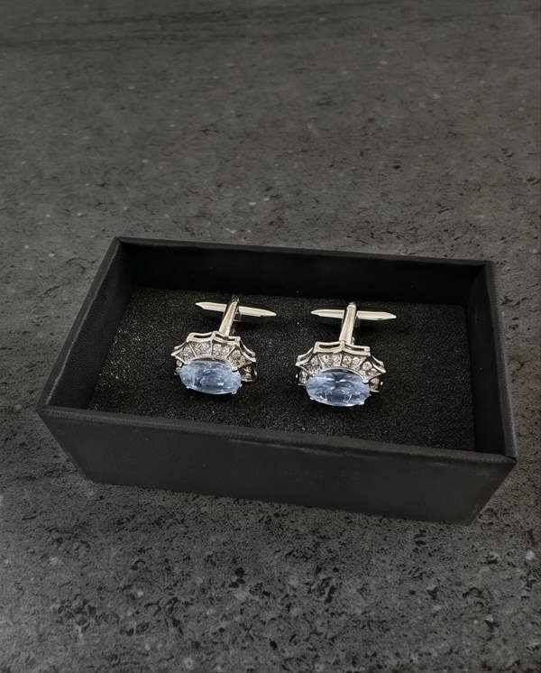 Pair of cufflinks with blue gemstones in a black box on a dark surface