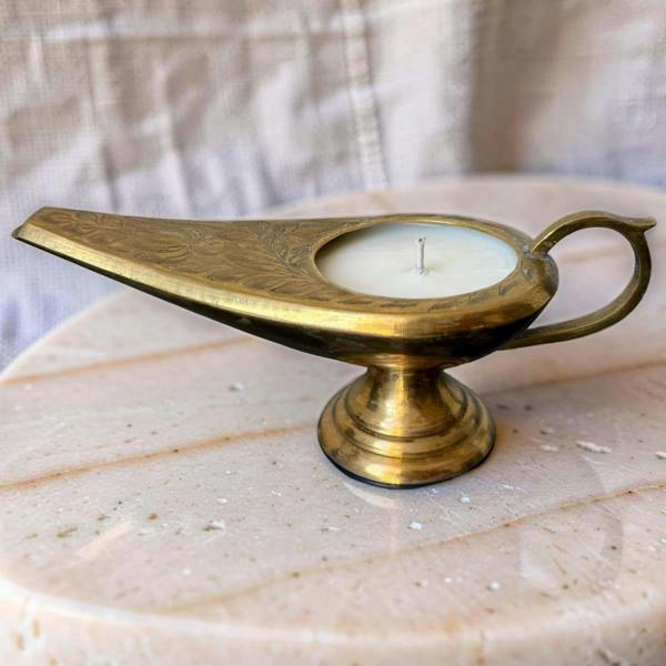 Brass lamp-shaped candle holder on a marble surface with a neutral background
