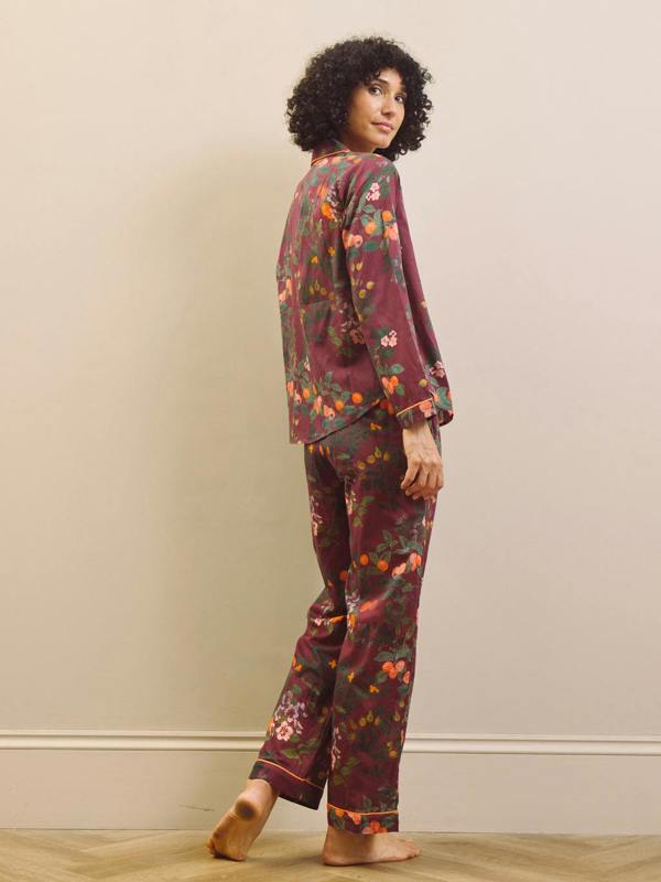 Woman wearing a burgundy floral pyjama set against a plain background