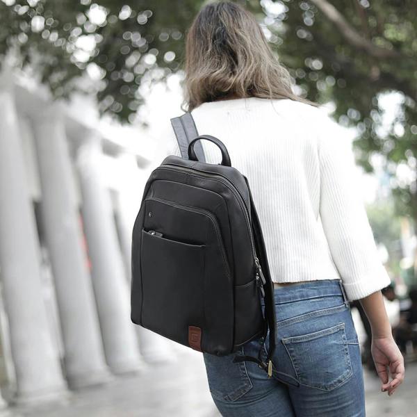 Person wearing a black backpack outdoors with blurred background