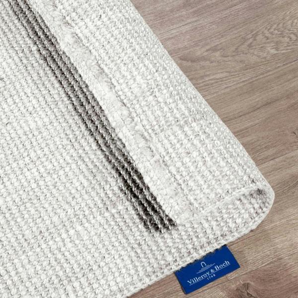 Textured white and gray rug with a Villero y Bosh label on a wooden floor.