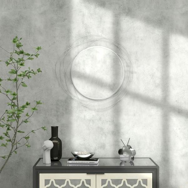 Silver round wall mirror with abstract metal wire loop frame on a wall