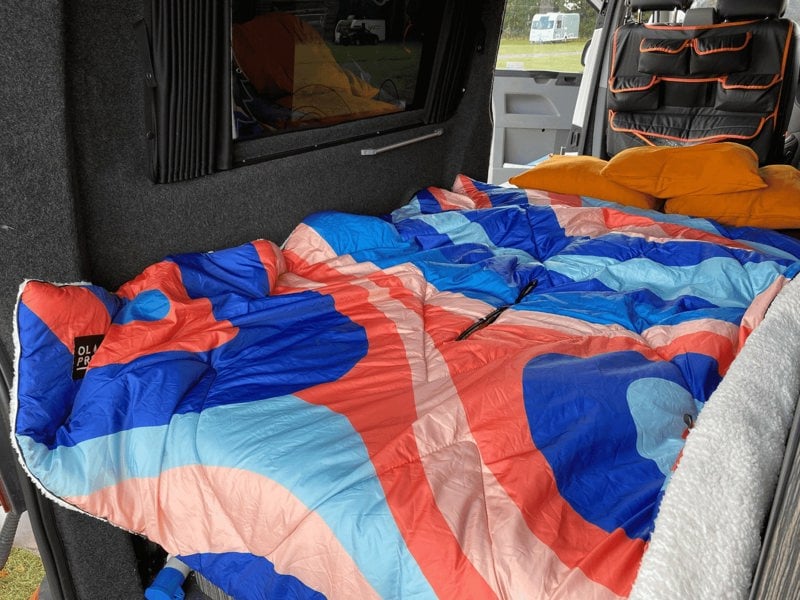 A Limited Edition OLPRO Ocean Sunset Blanko in the back of a campervan lay over the bed