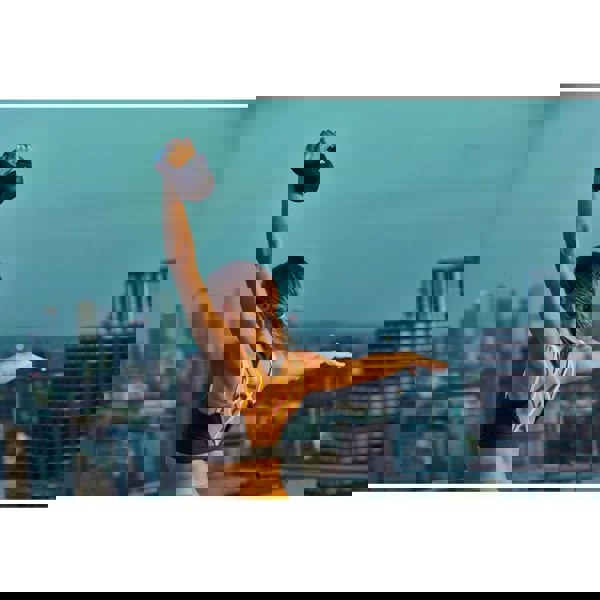 Person exercising with a 4kg adidas kettlebell on a rooftop with cityscape in the background