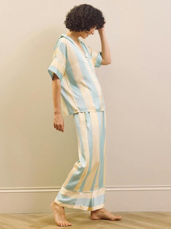 Woman wearing a striped pyjama set against a plain background