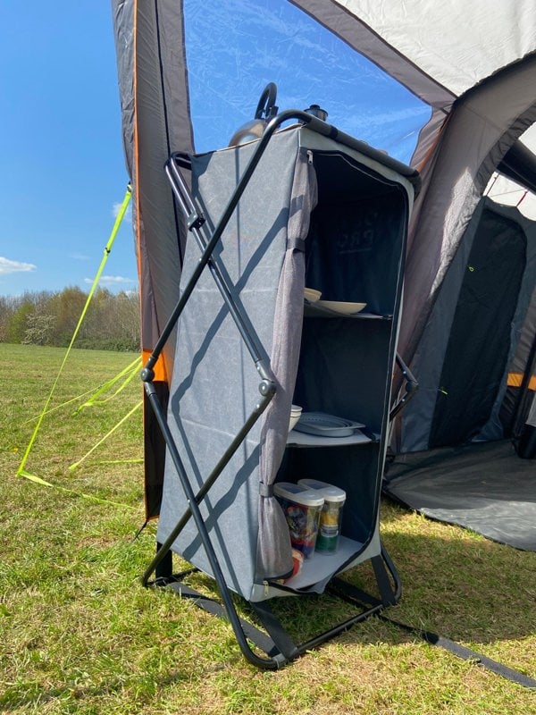 An image of the Collapsible Camp Storage Cupboard from OLPRO in a campervan awning pitched on a campsite.