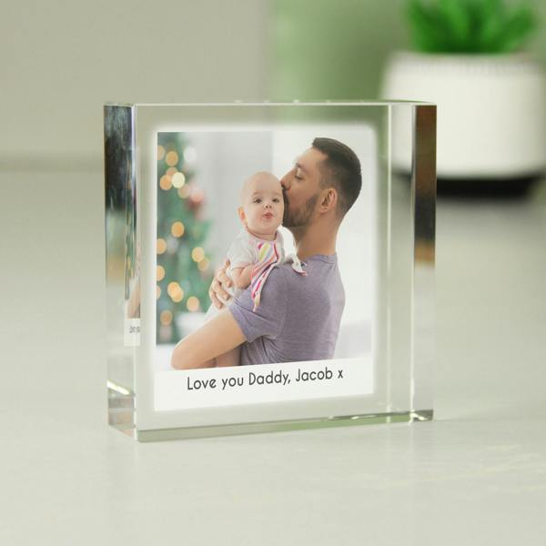 A freestanding square crystal photo block token showing a father kissing his baby with a blurred Christmas tree background.