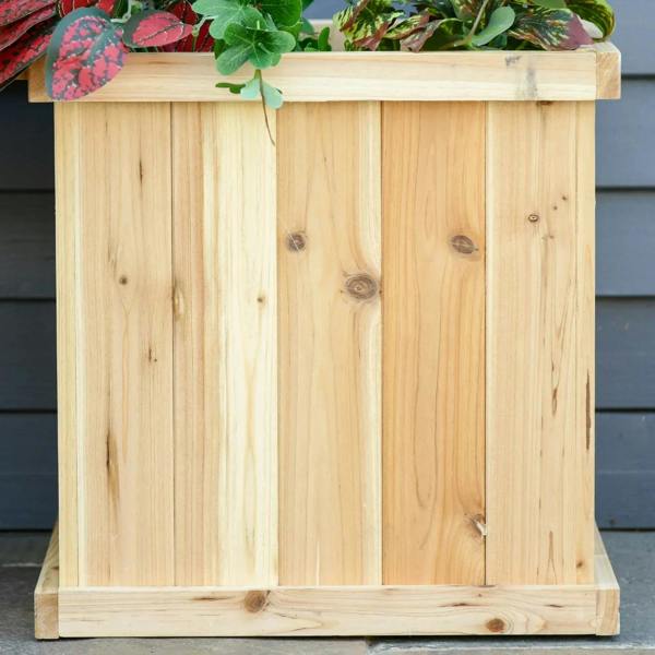 Natural wooden raised planter box with vertical planks and visible wood knots