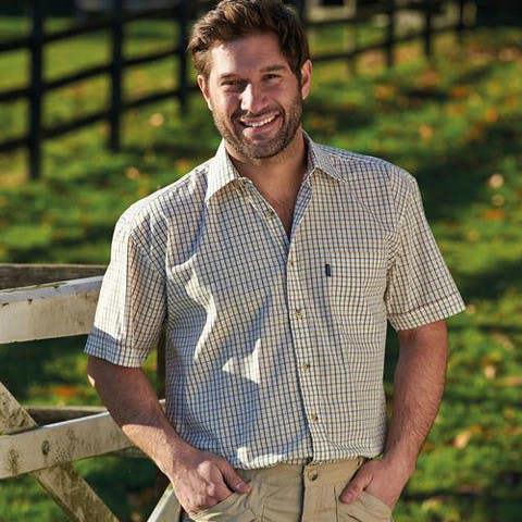 Man wearing Champion green Tattersall shirt in countryside setting, styled for warm weather comfort
