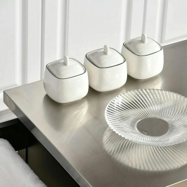 Stainless steel top with three canisters and a ridged tray on black kitchen island cart