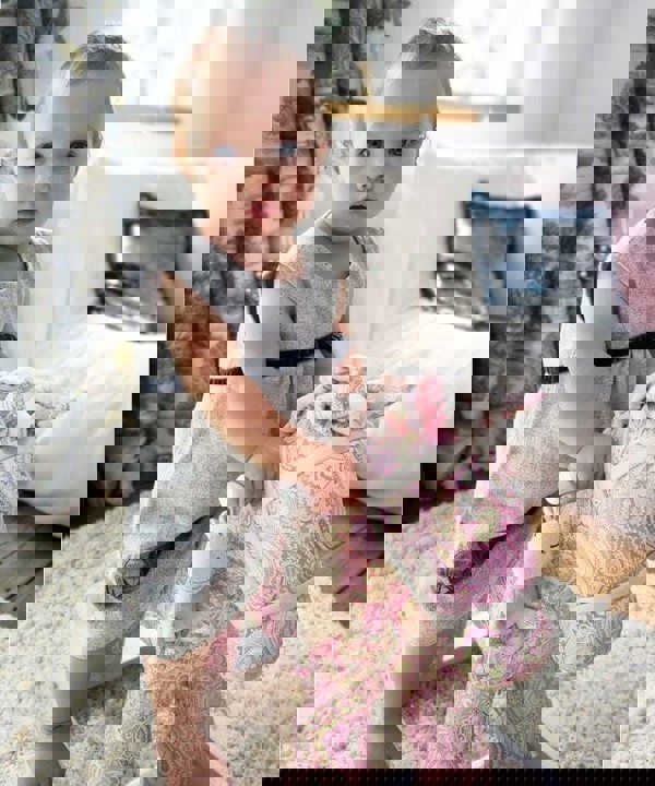 Little girl in grey dress riding Pixie & Fluff Rocking Horse 