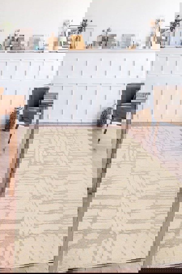 Ava Pave Wave Illusion Rug in cream, showcasing abstract design on wooden floor in stylish modern living room.