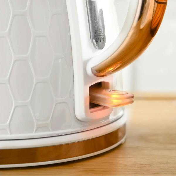 White electric kettle close-up showing illuminated power switch near copper spout