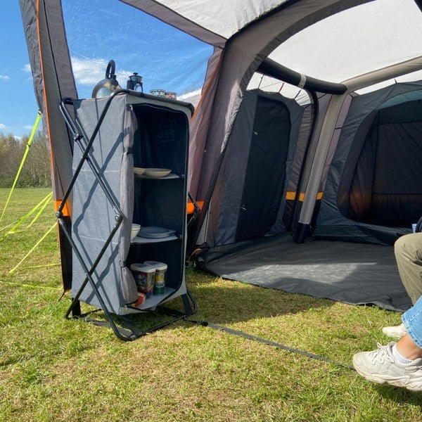 An image of the Collapsible Camp Storage Cupboard from OLPRO in a campervan awning pitched on a campsite.