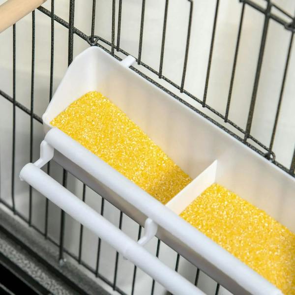 White feed cups with yellow seed inside dark grey bird cage wire
