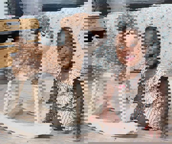 Infant girl sat next to Willow Rocking Dear on wooden floor